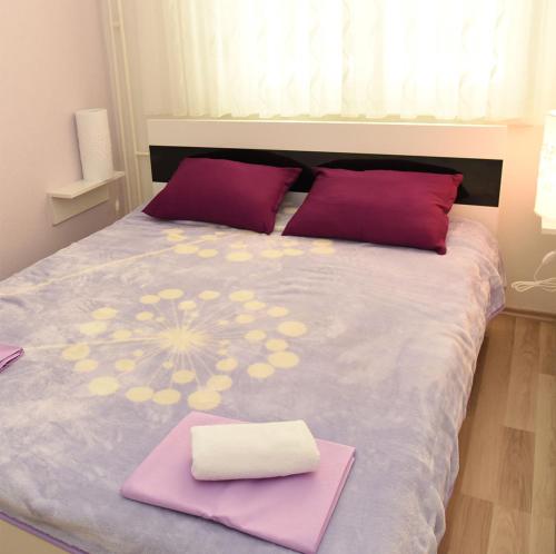 a bed with purple and yellow pillows on it at Angelina Apartment in Zaprešić