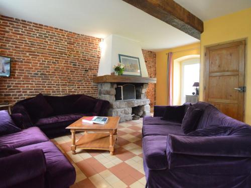 a living room with purple couches and a brick wall at house listed as an historic building near Montreuil in Gouy-Saint-André