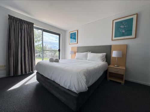 a bedroom with a large bed and a window at Ground Floor Spa Apartment Corrigans Cove in Batehaven