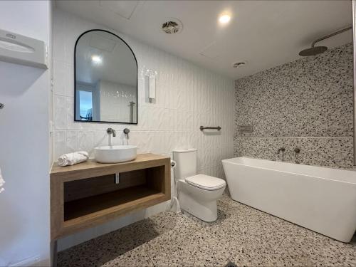 a bathroom with a tub and a toilet and a sink at Ground Floor Spa Apartment Corrigans Cove in Batehaven
