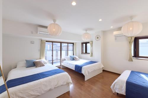 a bedroom with two beds and two windows at Shinagawa Villa in Tokyo