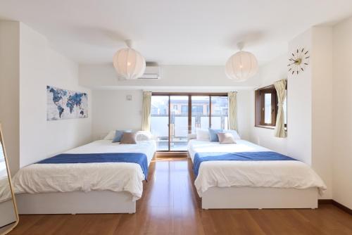 two beds in a room with white walls and wood floors at Shinagawa Villa in Tokyo