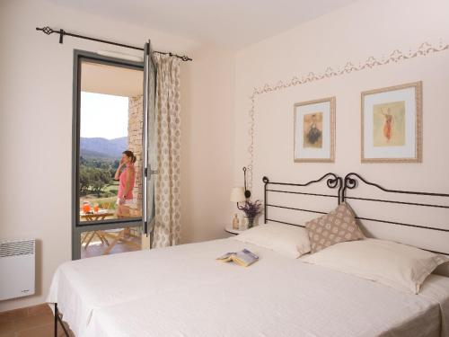 - une chambre avec un lit et une femme donnant sur la fenêtre dans l'établissement Charming apartment with dishwasher in Saumane de Vaucluse, à Saumane-de-Vaucluse