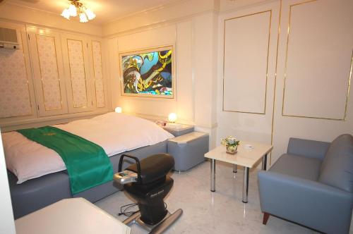 a bedroom with a bed and a couch and a chair at ホテルサティス伊勢店 in Ise