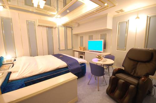 a bedroom with a bed and a desk and a chair at ホテルサティス伊勢店 in Ise