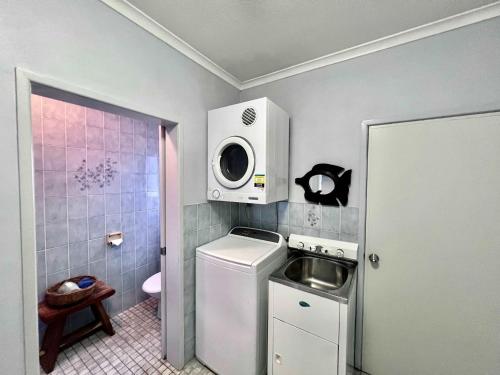 a small bathroom with a washing machine and a microwave at Flying Fish House in South Mission Beach