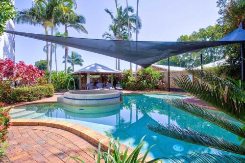 a swimming pool with a canopy and palm trees at 6 Ulysses - Spacious Beachfront Apartment in Mission Beach