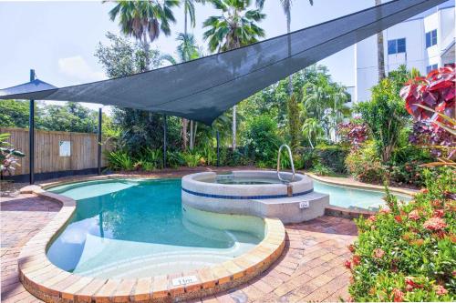 a swimming pool with a large umbrella over it at Ulysses 10 Ocean Dunk Island Views in Mission Beach