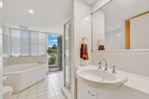 a white bathroom with a sink and a bath tub at Ulysses 10 Ocean Dunk Island Views in Mission Beach