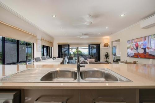a kitchen with a sink and a living room at Le Reve Wake up to sunrises and tropical breezes in Mission Beach