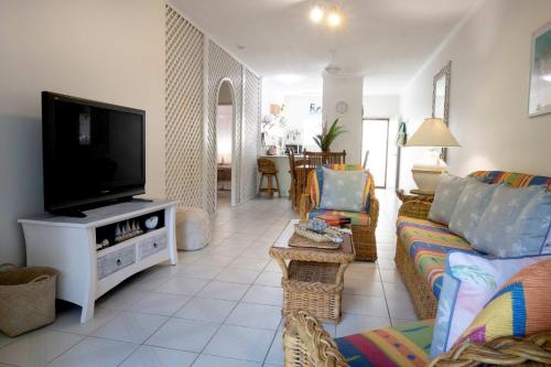 a living room with a couch and a flat screen tv at Kirrama 2 Pool across road to beach in Mission Beach
