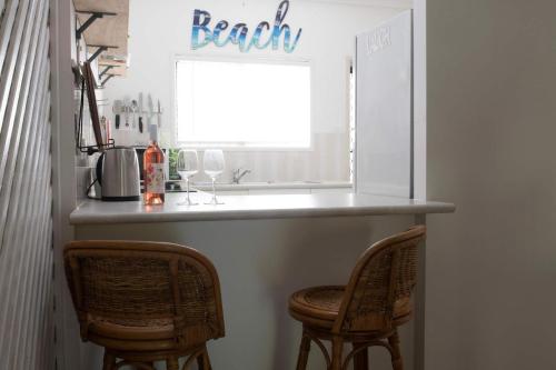 a kitchen with a bar with two chairs under it at Kirrama 2 Pool across road to beach in Mission Beach