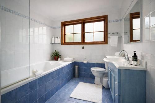 a bathroom with a tub and a toilet and a sink at Blue Mountains charm with Spa! in Wentworth Falls