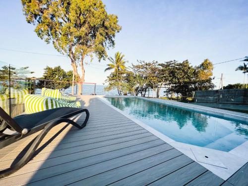 a swimming pool with chaise lounge chairs on a wooden deck at Bella Luna Beach Front 2 bed in South Mission Beach