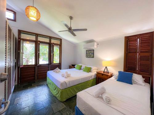 a bedroom with two beds and a ceiling fan at Wongalinga Absolute Beachfront Unit 9 2 Bedroom in Mission Beach
