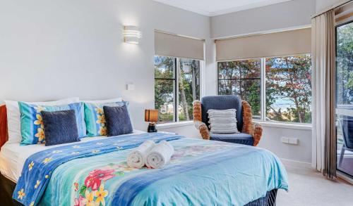 a bedroom with a bed and a chair and windows at Ulysses One Beachfront Escape 1 Bedroom in Mission Beach