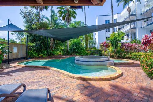 a swimming pool with a hammock in a courtyard at Ulysses One Beachfront Escape 1 Bedroom in Mission Beach