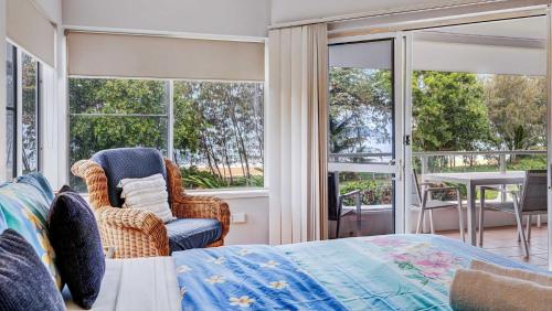 a bedroom with a bed and a chair and windows at Ulysses One Beachfront Escape 2 Bedroom Spacious in Mission Beach