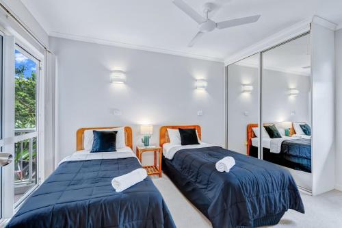 two beds in a room with a mirror at Ulysses One Beachfront Escape 2 Bedroom Spacious in Mission Beach