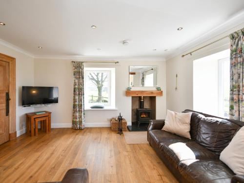 a living room with a leather couch and a fireplace at Heron View in Kirkcudbright