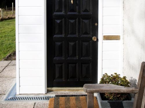 a black door with a bench in front of it at Mill Cottage-Uk7348 in Dyke