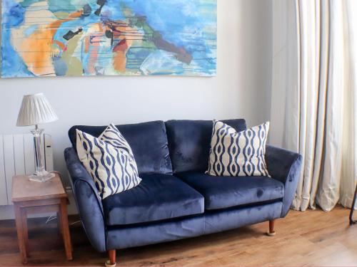 a blue couch in a living room with a painting at Seaside Apartment-Uk2801 in Aberystwyth