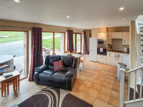 a living room with a leather couch and a kitchen at The Stables - Uk7791 in Milton of Auchinhove