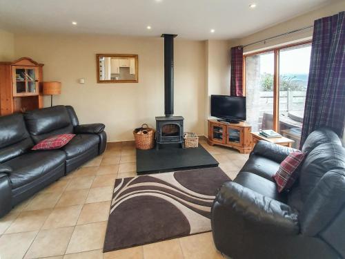 a living room with a leather couch and a fireplace at The Stables - Uk7791 in Milton of Auchinhove