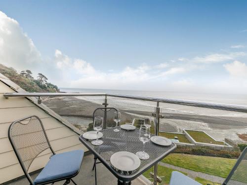 a table and chairs on a balcony with a view of the ocean at 23 Mount Brioni in Downderry