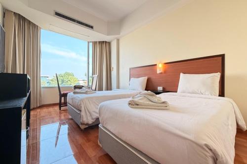 two beds in a hotel room with a large window at The Grand Imperial in Ban Song Hong