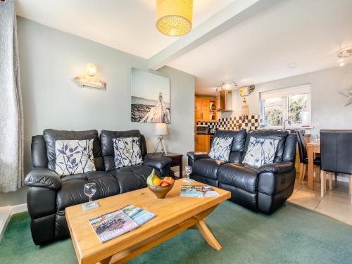 a living room with a leather couch and a table at 6 Mount Brioni in Downderry