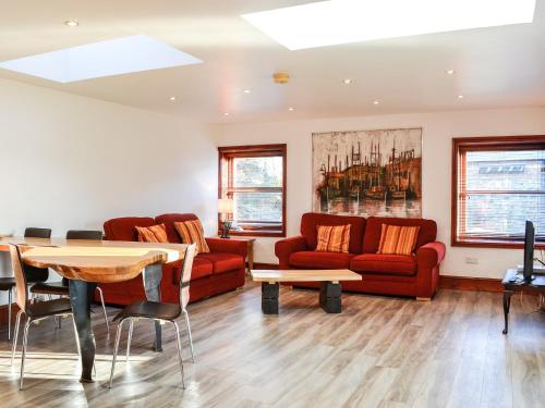 a living room with red couches and a table at Anne's Cottage - Uk7782 in Newton Stewart