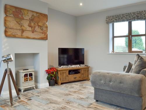 a living room with a couch and a flat screen tv at The Corn Store in Malpas