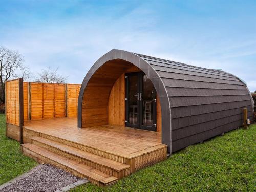 a small building with a wooden deck in the grass at Chestnut-Uk7586 in Stewarton