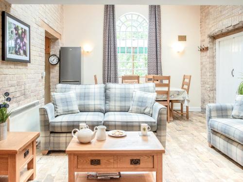 a living room with a couch and a table at Stearn Cottage-17917 in Langham