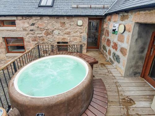 a large hot tub sitting on a deck next to a building at The Byre - Uk7790 in Milton of Auchinhove
