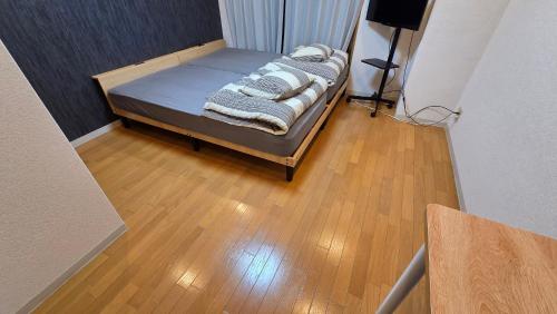a small bed in a room with a wooden floor at MORI Apartment Near namba in Osaka