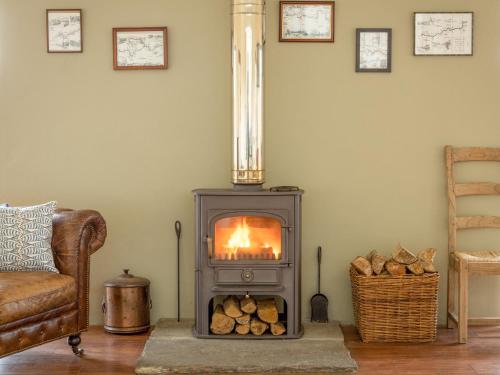 a wood burning stove in a living room with a chair at Ford Cottage in Banchory