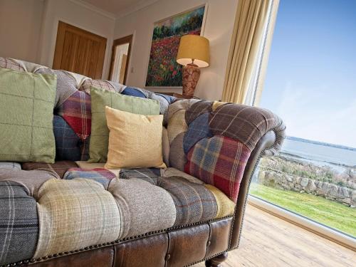 a couch with pillows in a living room with a window at Edenville in Girthon