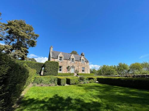 an old brick house with a green yard at Balloan Cottage-Uk7382 in Dornoch