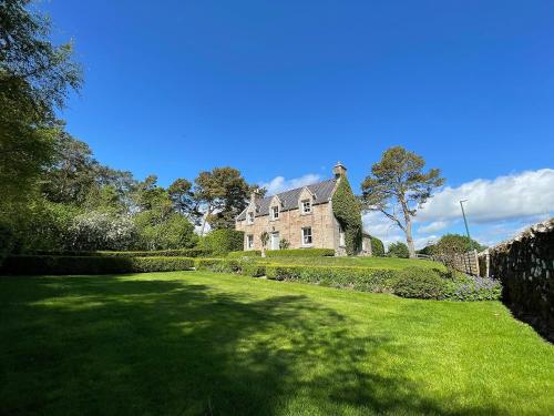 an old house with a large lawn in front of it at Balloan Cottage-Uk7382 in Dornoch