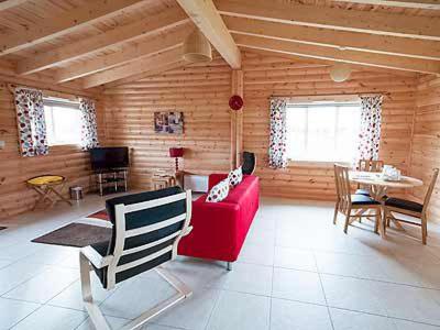 a living room with a red couch and a table at Kingfisher Lodge- W43170 in Burn