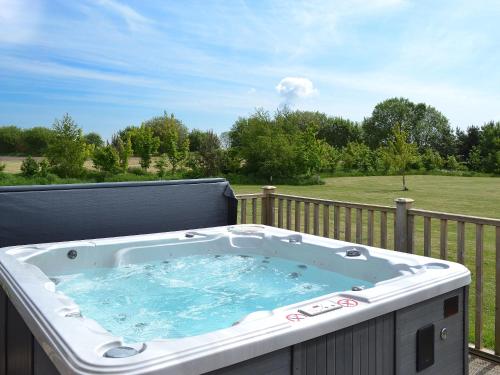 a jacuzzi tub on a deck with a view of a field at Kingfisher Lodge- W43170 in Burn