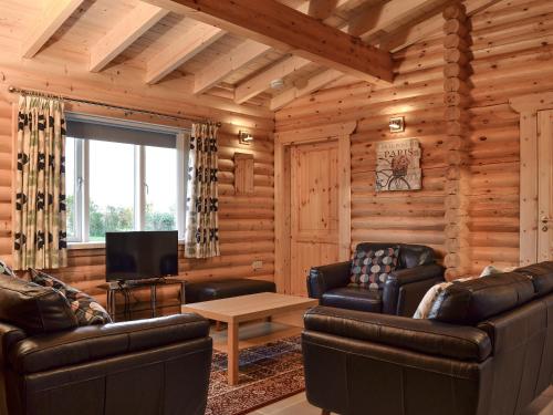 a living room with leather furniture in a log cabin at Teal Lodge- Ukc2565 in Burn