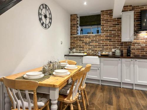 a kitchen with a table with chairs and a clock on the wall at Coachmans Cottage in Settle