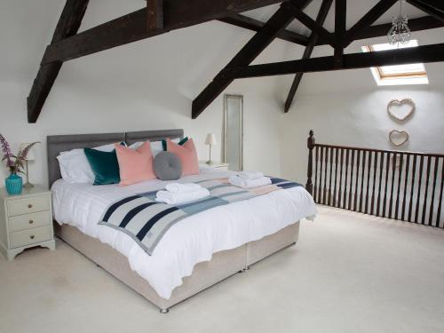 a bedroom with a large bed with colorful pillows at The Coach House - Ukc4691 in Kilkhampton