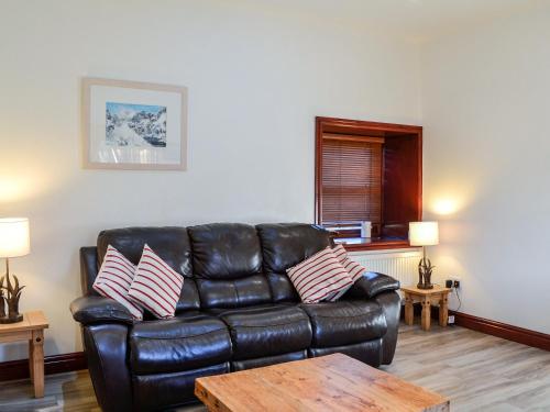 a black leather couch in a living room with a table at Merrick Cottage - Uk7783 in Newton Stewart