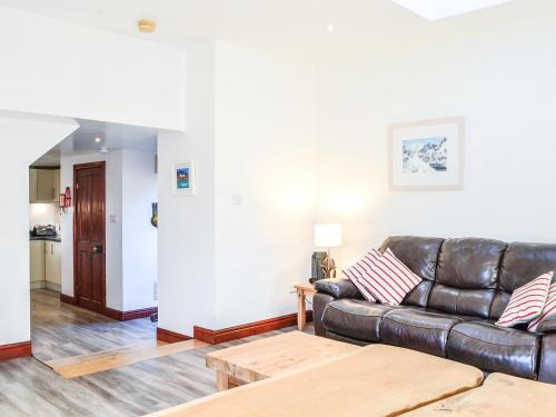 a living room with a leather couch and a table at Merrick Cottage - Uk7783 in Newton Stewart