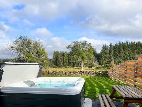 a hot tub sitting on a patio next to a bench at Maberry Cottage - Uk7784 in Newton Stewart