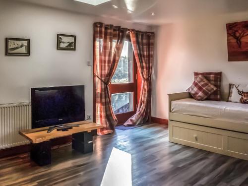 a living room with a couch and a tv and a window at Maberry Cottage - Uk7784 in Newton Stewart